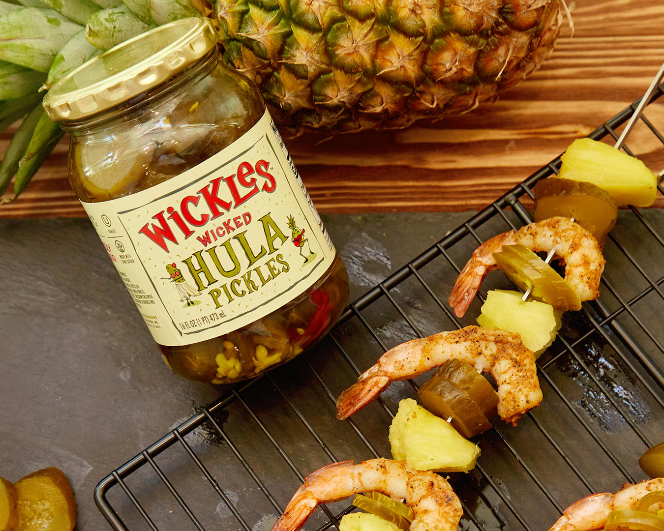 wicked hula shrimp kebabs sitting on grill grate next to a jar of wickles hula pickles